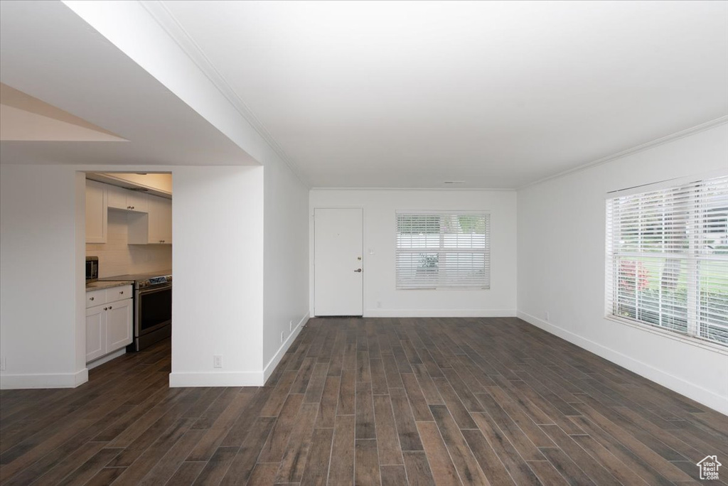 Unfurnished living room with baseboards, ornamental molding, and dark wood-style flooring