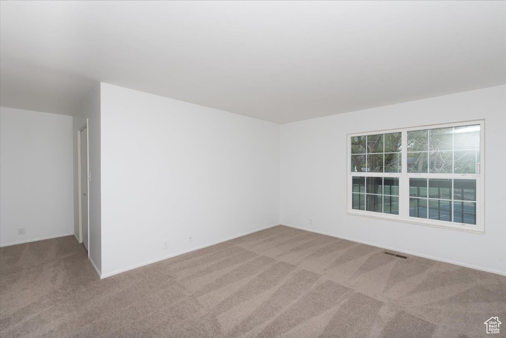 Carpeted spare room with visible vents and baseboards