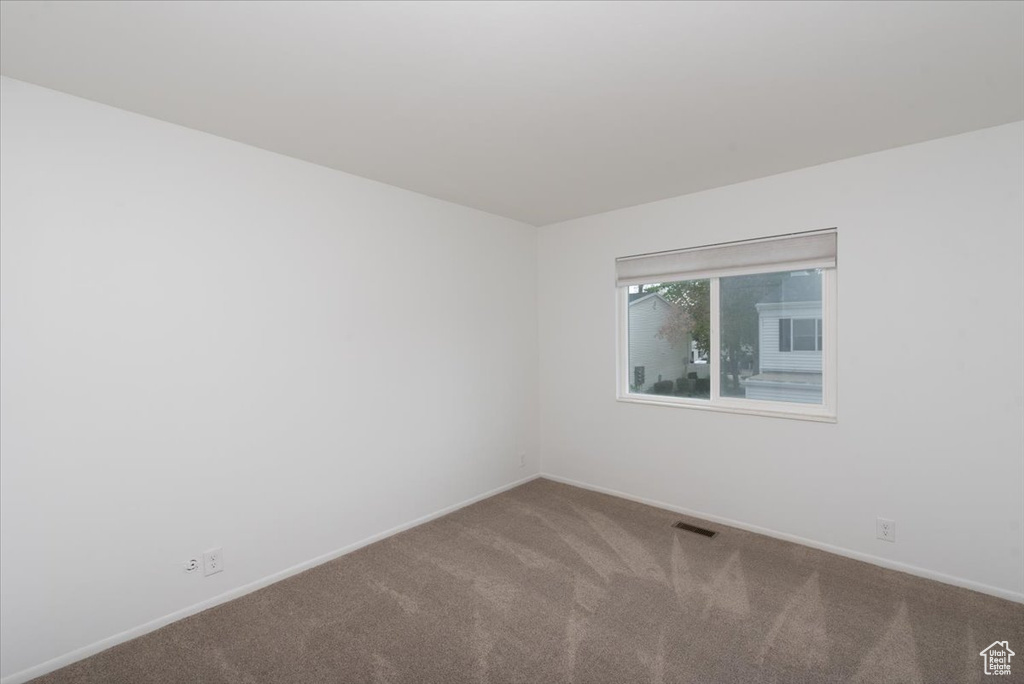 Carpeted empty room featuring visible vents and baseboards