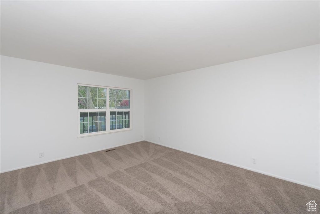 Spare room featuring baseboards, visible vents, and carpet flooring