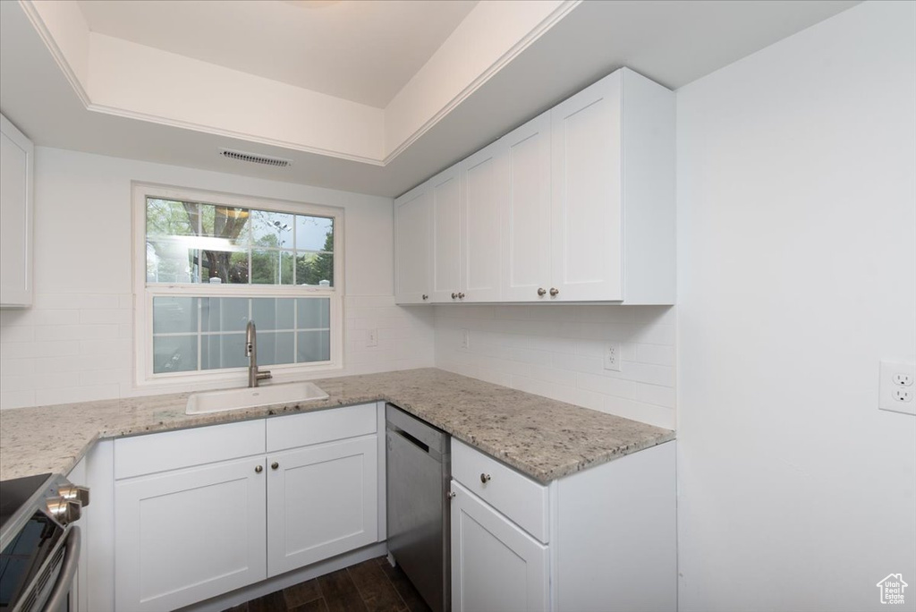 Kitchen with stainless steel appliances, backsplash, a sink, white cabinetry, and visible vents