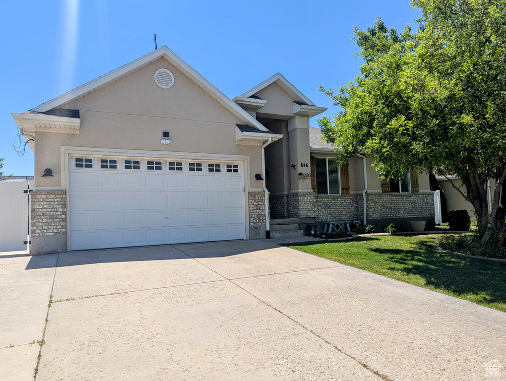 Single story home with brick siding, a garage, concrete driveway, and stucco siding