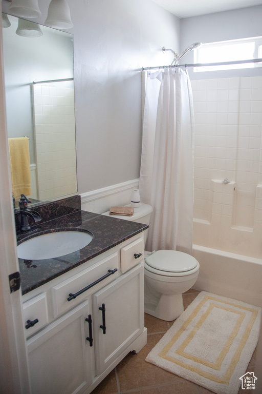 Bathroom with vanity, toilet, tile patterned flooring, and shower / tub combo with curtain