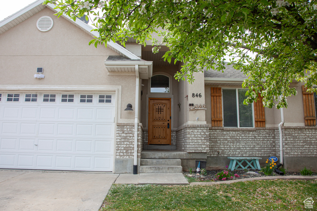 View of front of property with concrete driveway, an attached garage, and stucco siding