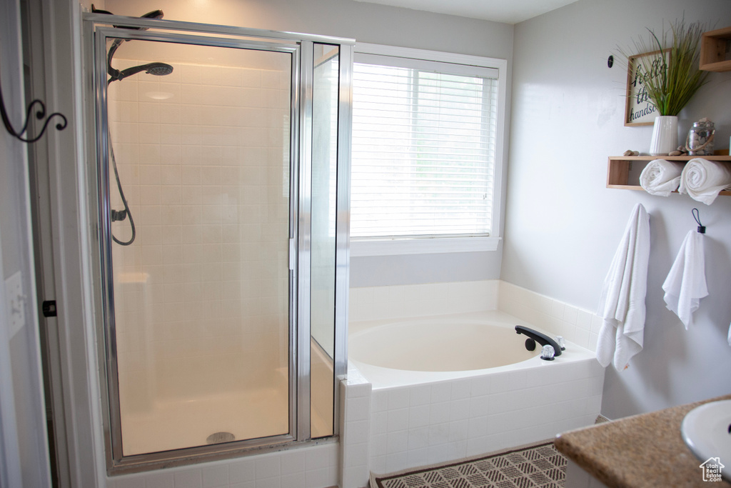Bathroom with a garden tub, vanity, and a stall shower