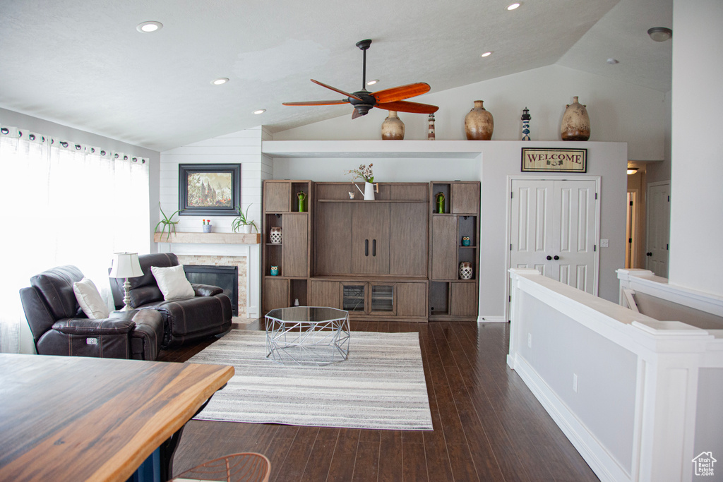Living area featuring dark wood-style floors, recessed lighting, a ceiling fan, a stone fireplace, and lofted ceiling