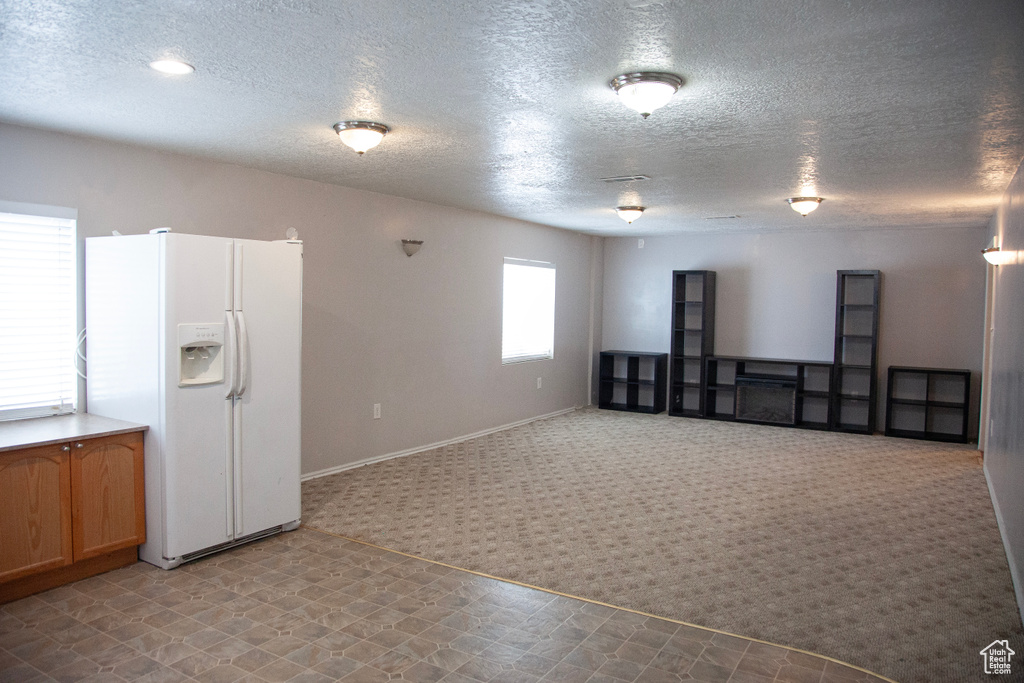 Carpeted empty room with a textured ceiling and baseboards