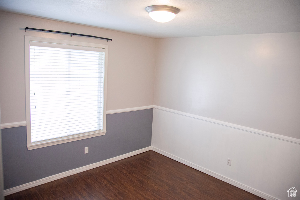 Unfurnished room with dark wood-style flooring, plenty of natural light, and baseboards