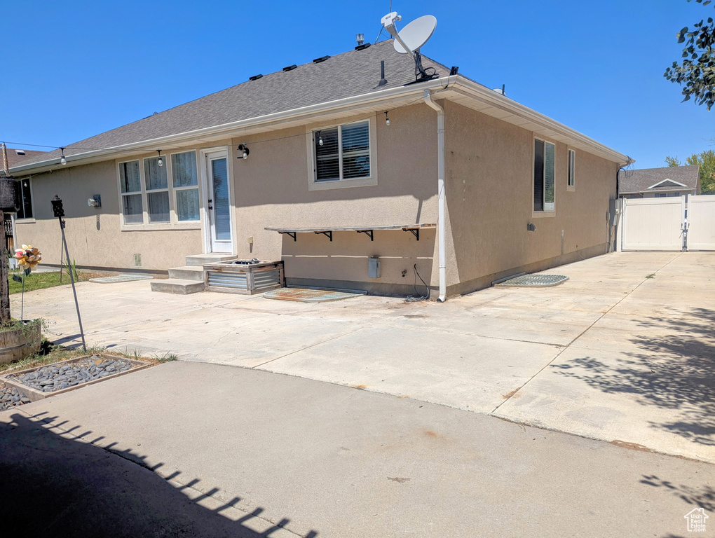 Rear view of property with stucco siding, a patio area, a garage, and driveway