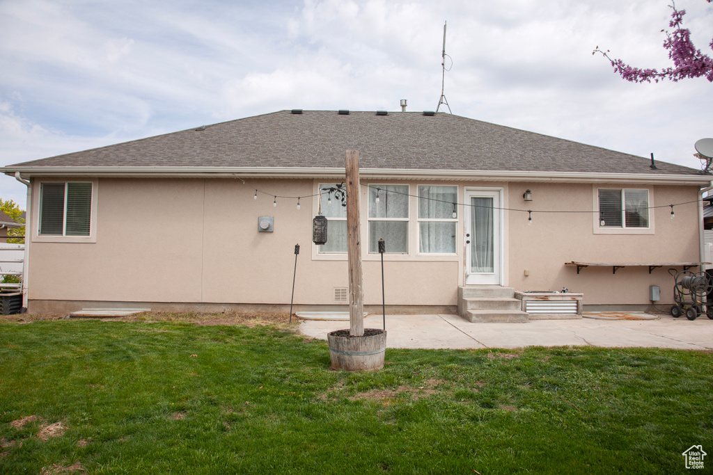 Rear view of house with stucco siding, a yard, entry steps, roof with shingles, and a patio area
