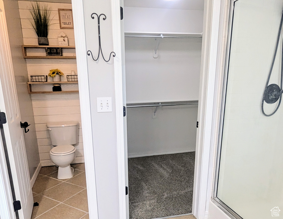 Full bath with a walk in closet, tile patterned flooring, and a stall shower
