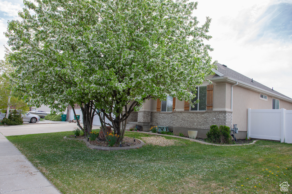 View of front facade with brick siding, fence, driveway, a front lawn, and an attached garage