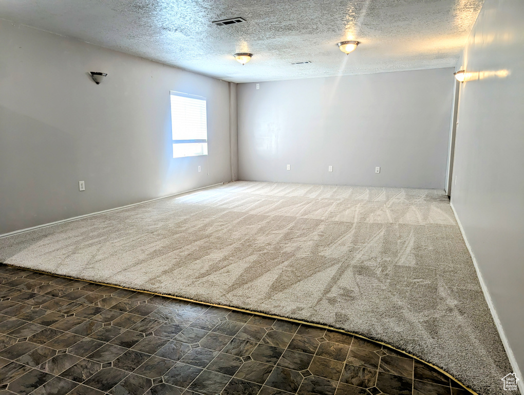 Carpeted empty room featuring a textured ceiling