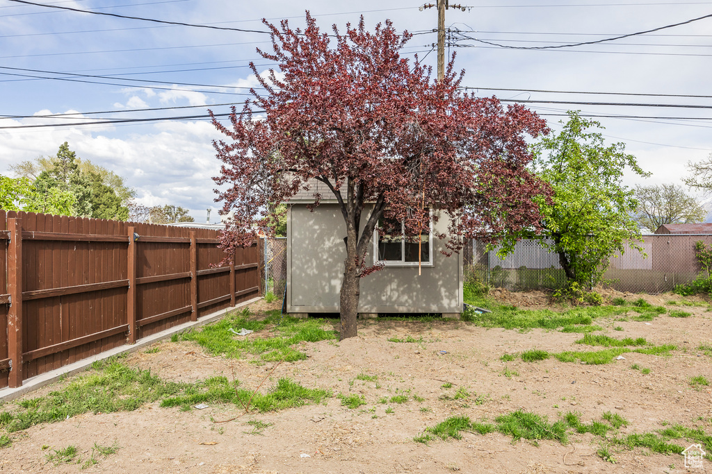 View of yard featuring a storage unit, an outbuilding, and a fenced backyard