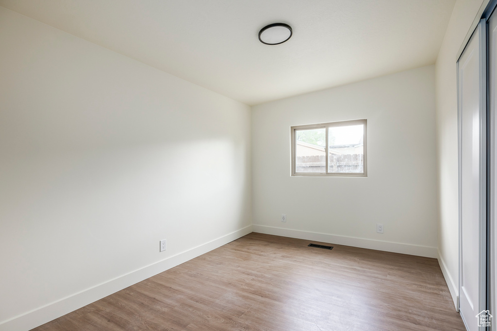 Empty room with visible vents, light wood-style floors, and baseboards
