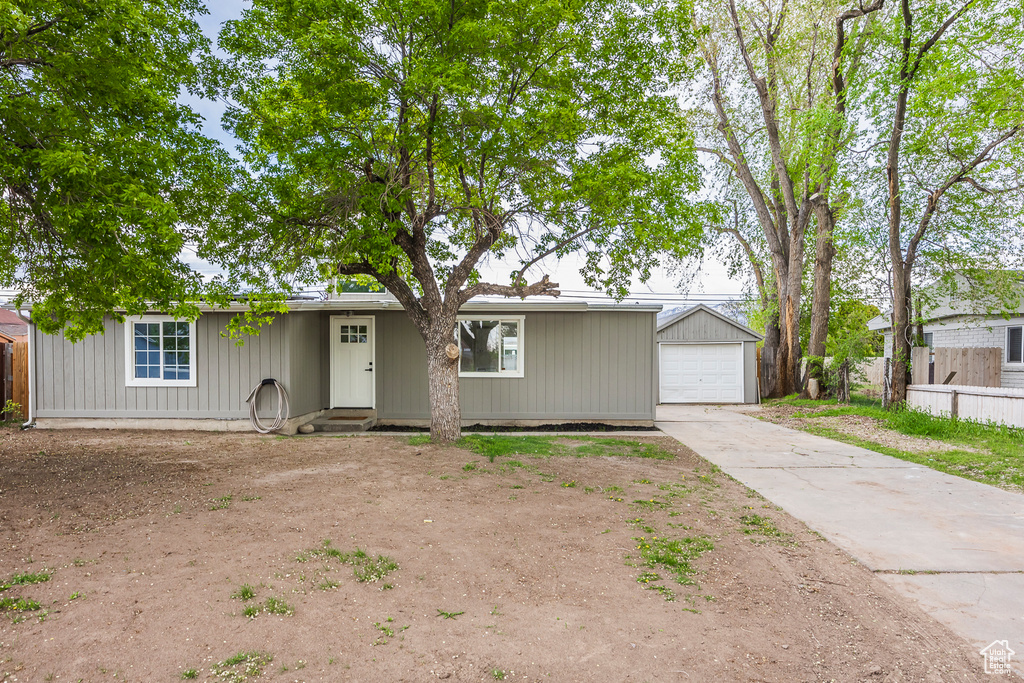 Single story home with an outbuilding, concrete driveway, a garage, and fence