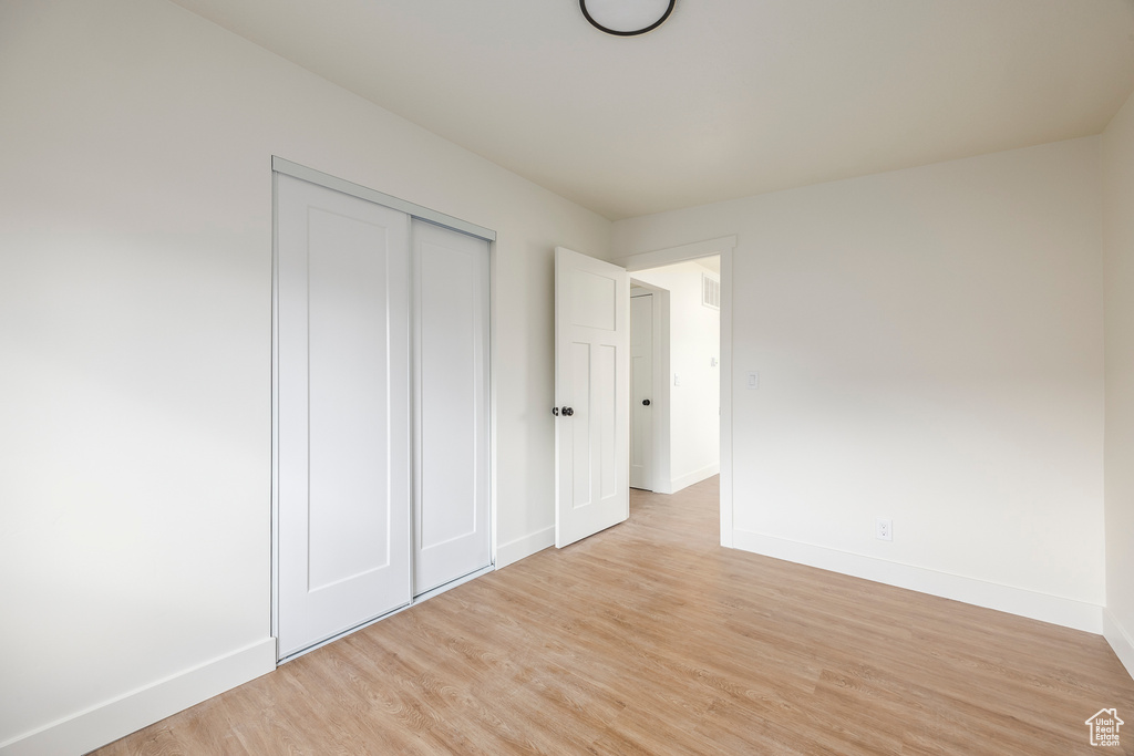 Unfurnished bedroom featuring baseboards, visible vents, a closet, and light wood finished floors