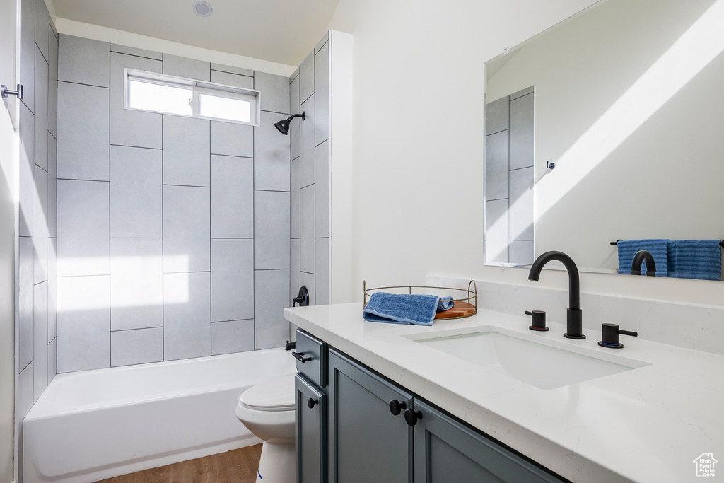 Bathroom featuring wood finished floors, toilet, shower / tub combination, and vanity