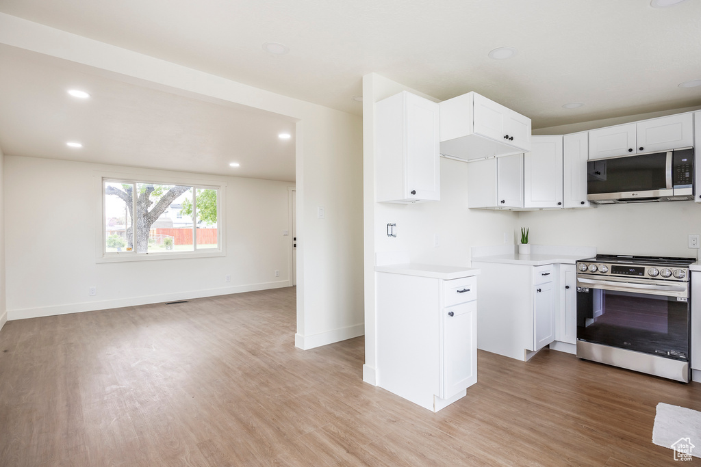 Kitchen featuring recessed lighting, light wood-style flooring, appliances with stainless steel finishes, light countertops, and white cabinetry