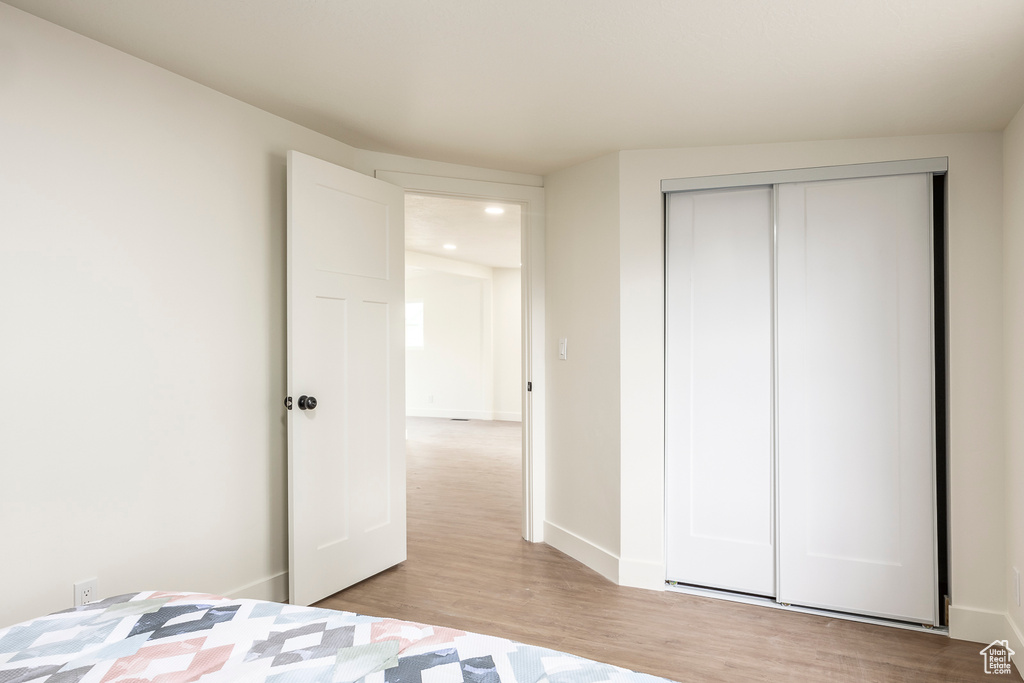 Unfurnished bedroom featuring light wood finished floors, a closet, recessed lighting, and baseboards