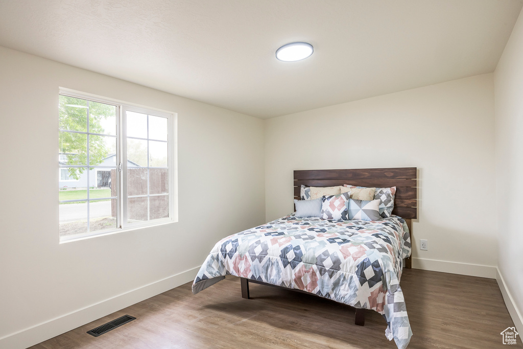 Bedroom with visible vents, wood finished floors, and baseboards