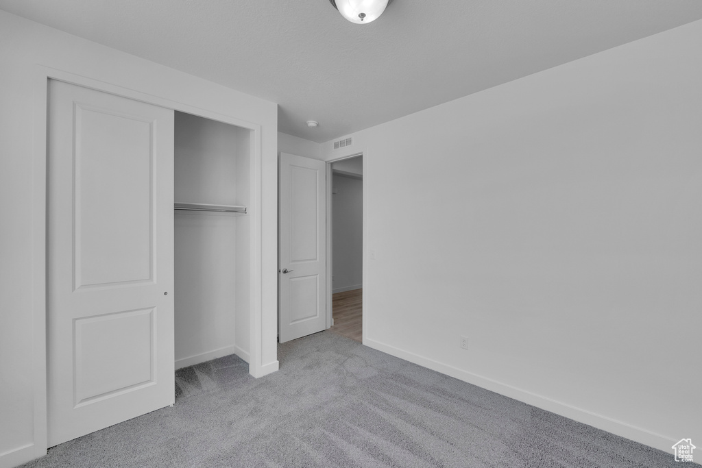 Unfurnished bedroom featuring carpet flooring, baseboards, and a closet