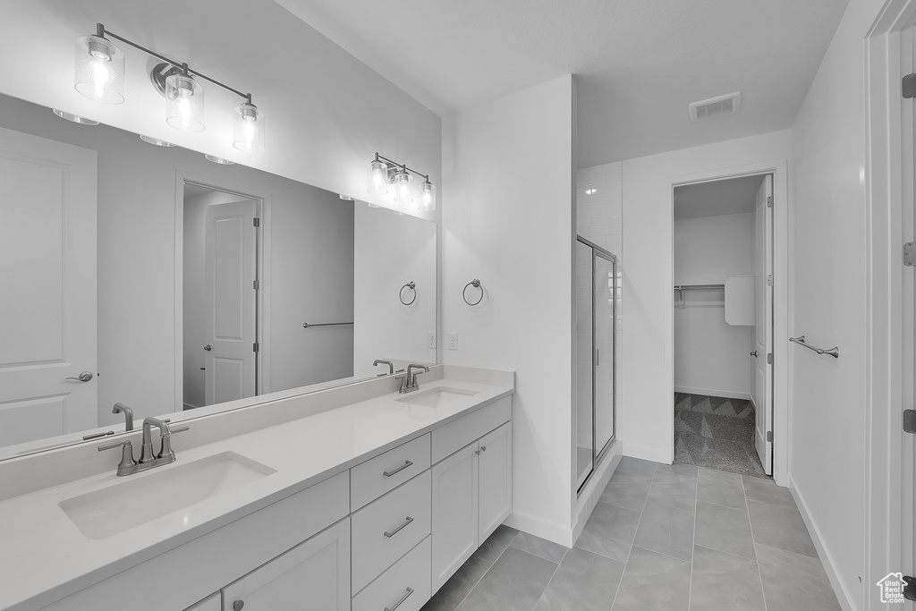 Bathroom with a shower stall, double vanity, a spacious closet, and baseboards