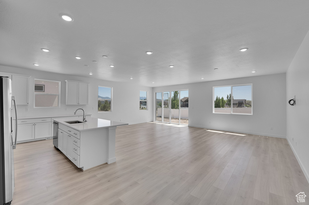 Kitchen with a sink, freestanding refrigerator, open floor plan, recessed lighting, and healthy amount of natural light