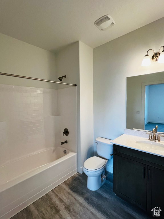 Bathroom with wood finished floors, bathtub / shower combination, toilet, vanity, and visible vents
