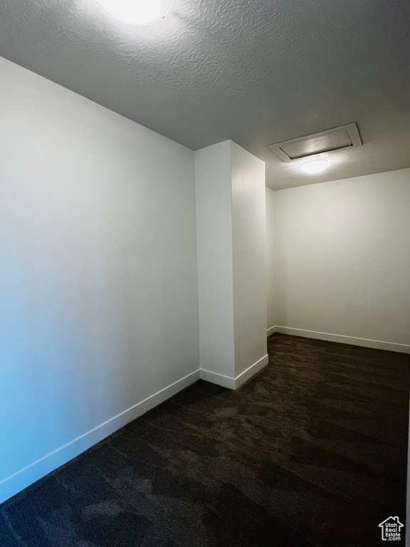 Unfurnished room featuring dark colored carpet and baseboards