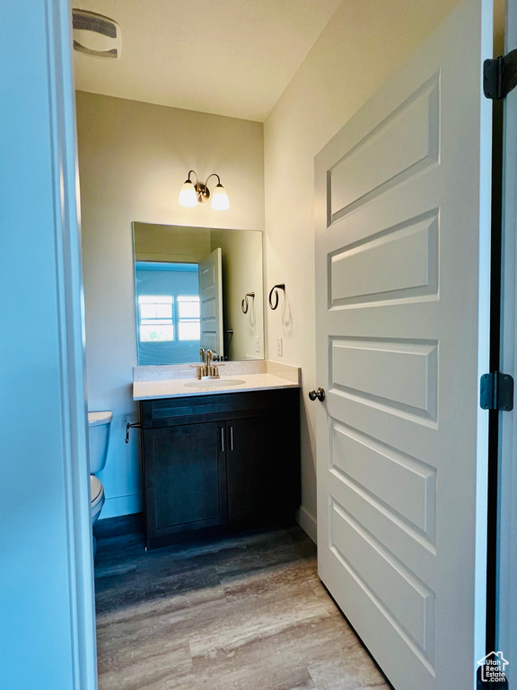 Bathroom featuring visible vents, wood finished floors, toilet, and vanity