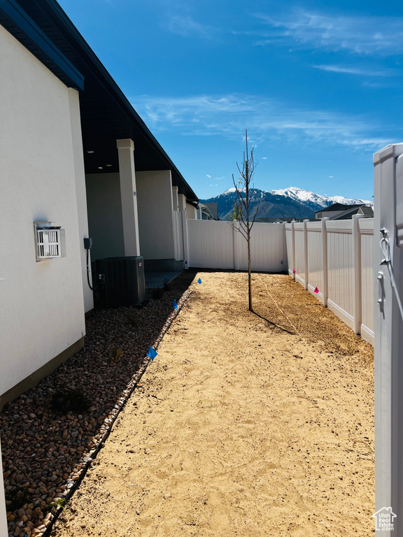 View of yard featuring central air condition unit, a mountain view, and a fenced backyard