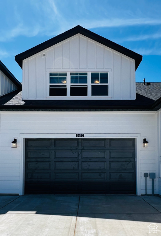 View of side of home featuring driveway, board and batten siding, and a garage