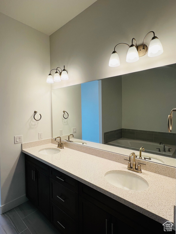 Full bathroom featuring double vanity, a sink, and baseboards
