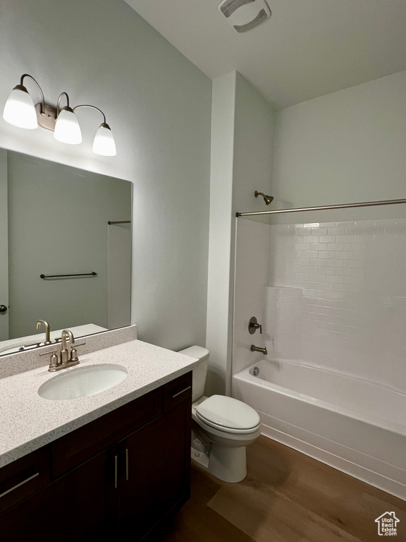 Bathroom featuring shower / washtub combination, wood finished floors, toilet, and vanity