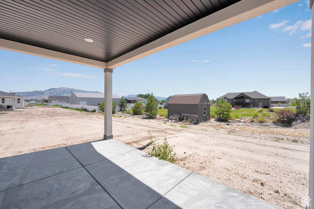 View of patio / terrace with a residential view, a storage unit, and a mountain view