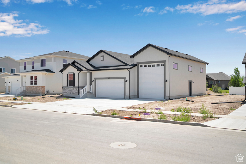 View of front of property featuring a garage, concrete driveway, and stucco siding