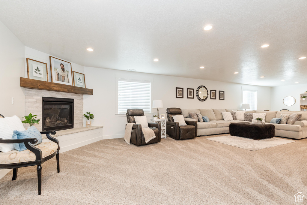 Carpeted living room featuring a healthy amount of sunlight, a tiled fireplace, recessed lighting, and baseboards