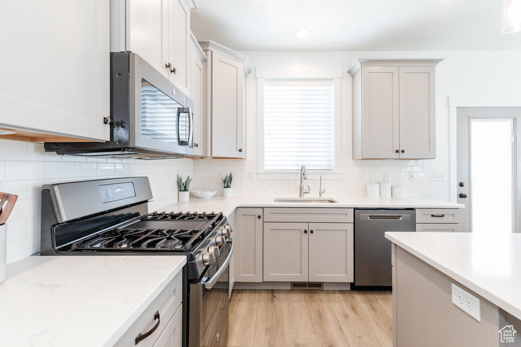 Kitchen featuring visible vents, appliances with stainless steel finishes, tasteful backsplash, a sink, and light wood-style flooring