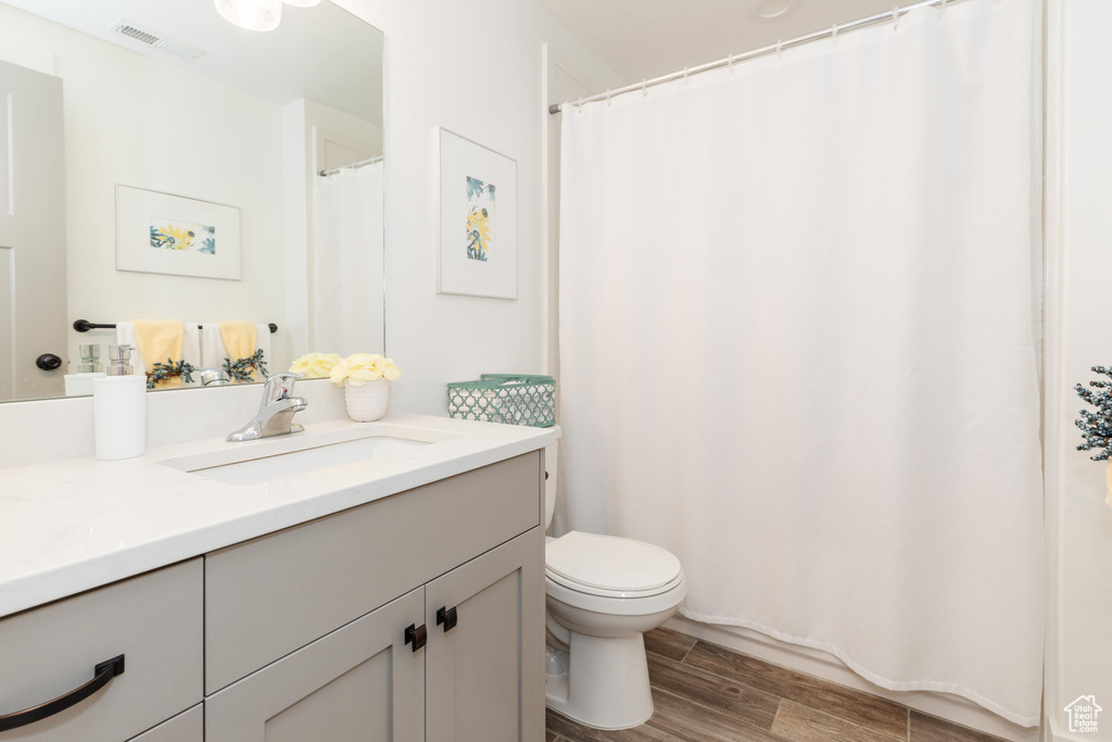 Full bath featuring visible vents, wood finished floors, toilet, and vanity