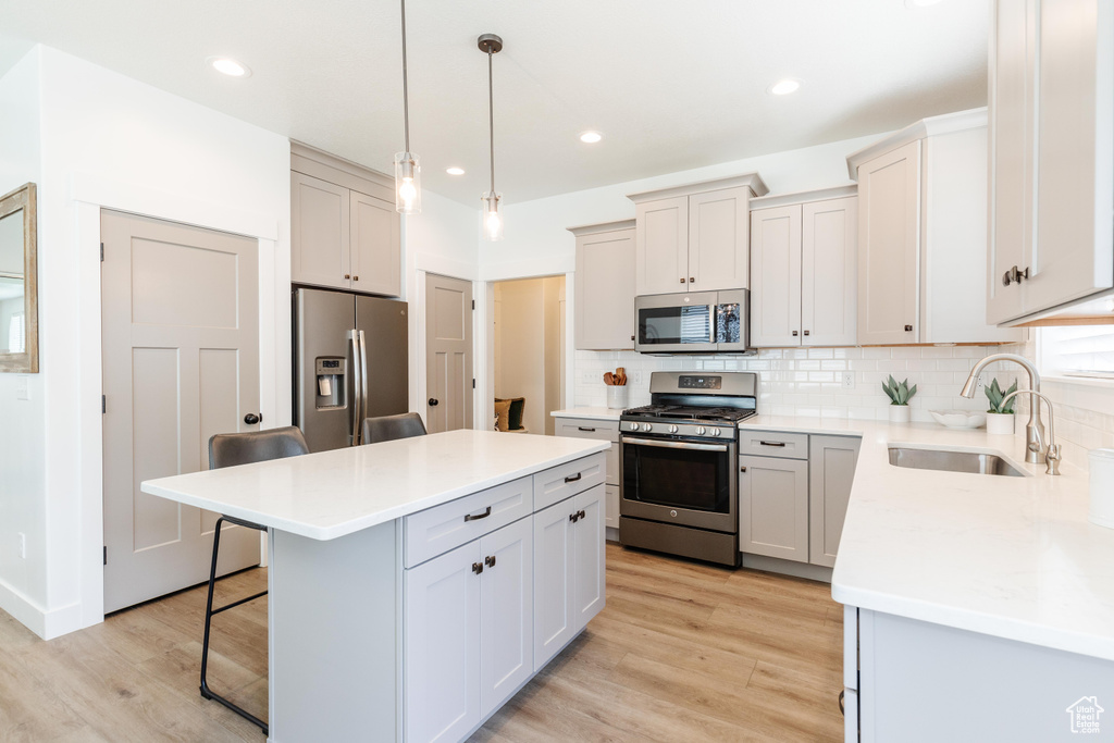 Kitchen featuring a sink, backsplash, a kitchen bar, and stainless steel appliances