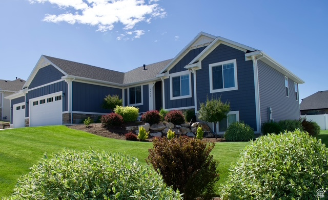 View of front of property featuring board and batten siding, a front yard, and an attached garage