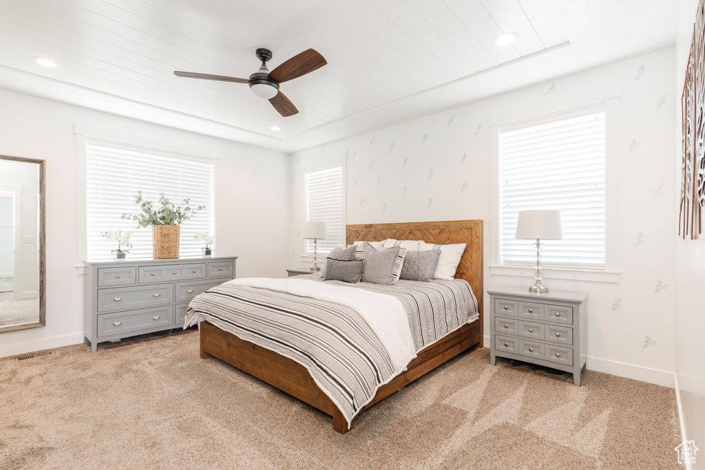 Bedroom with baseboards, light carpet, and multiple windows