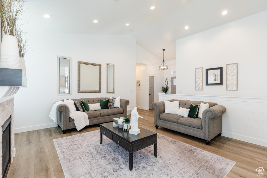 Living area with baseboards, light wood-style flooring, high vaulted ceiling, and a fireplace