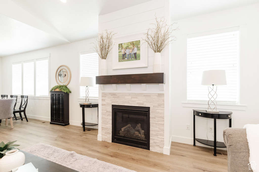 Living room with baseboards, wood finished floors, a tile fireplace, and vaulted ceiling