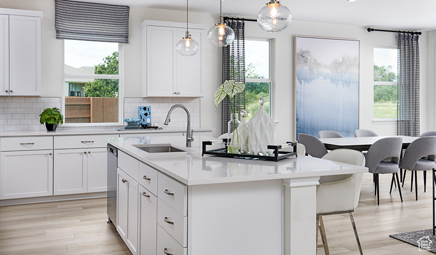 Kitchen with light countertops, a sink, tasteful backsplash, and a center island with sink