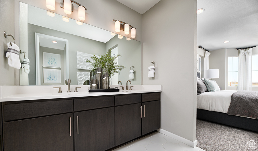 Ensuite bathroom featuring a sink, connected bathroom, double vanity, baseboards, and tile patterned flooring