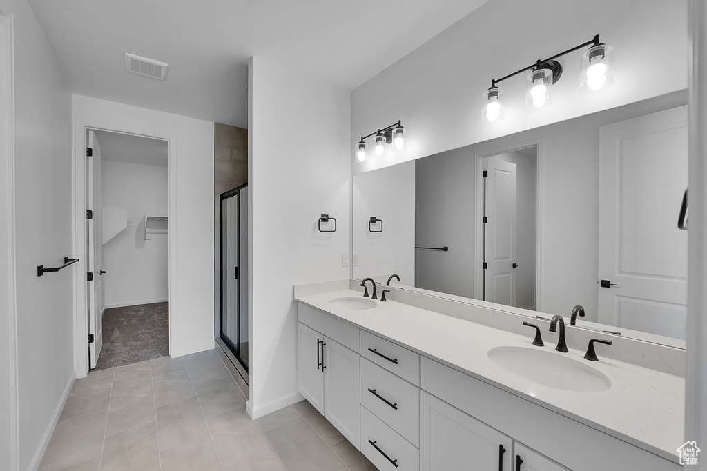 Bathroom featuring a stall shower, double vanity, a spacious closet, and tile patterned floors