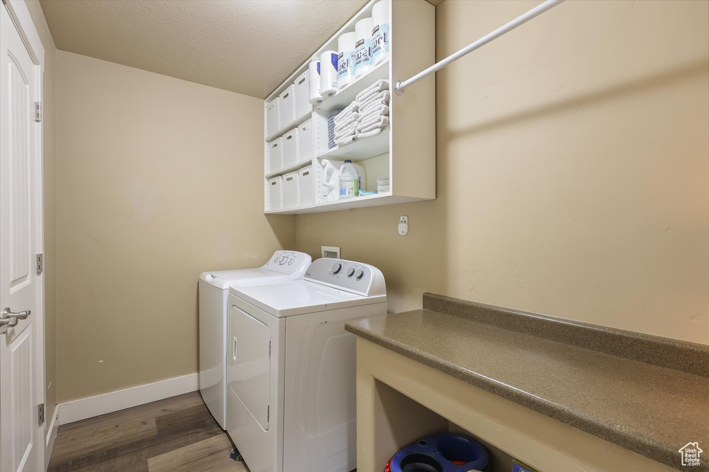 Laundry room with wood finished floors, washer and clothes dryer, laundry area, and baseboards