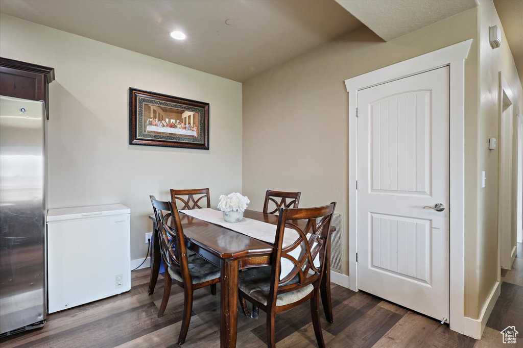 Dining room with dark wood-type flooring, visible vents, recessed lighting, and baseboards
